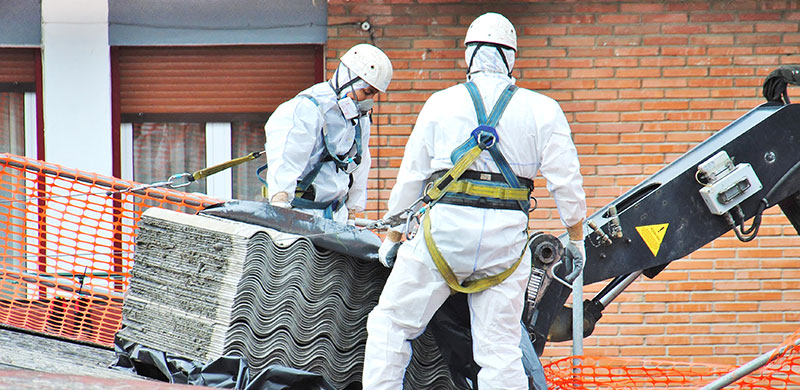 Bei Asbest in Bitumen sind Schutzanzüge Pflicht bei der Entsorgung von Bauabfällen.