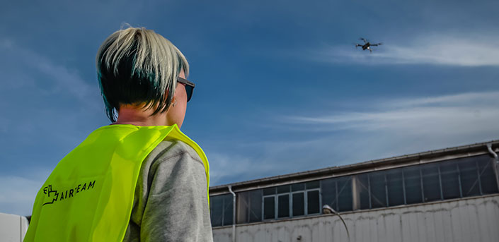 EU-Drohnenverordnung: Foto von Airteam Drohnenpilotin mit Drohne über Fabrikgebäude.