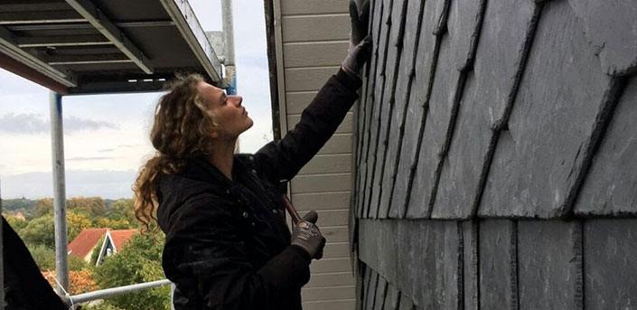 Bild von Dachdeckerin Sabrina Jung bei der Arbeit an der Schiefer-Fassade