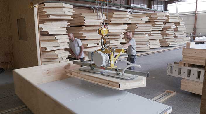 Bild von Mitarbeitern beim Transport der Hohlkassetten für das Gebäude in Holzleichtbauweise 