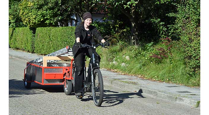 Bild von Inseldachdeckerin Johanna Rieger auf dem Fahrrad, wie sie Material transportiert