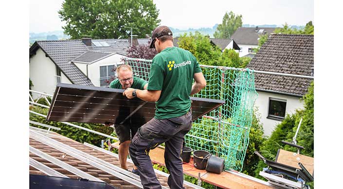 Bild von Mitarbeitern von BonnSolar mit Solarmodul auf dem Dach