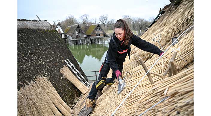 Bild von Reetdachdeckerin Moira Memmhardt bei der Arbeit im Freilichtmuseum