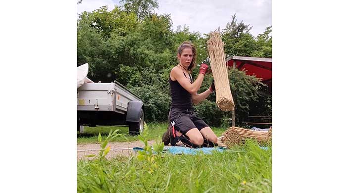 Bild von Reetdachdeckerin Moira Memmhardt mit Reetbündel