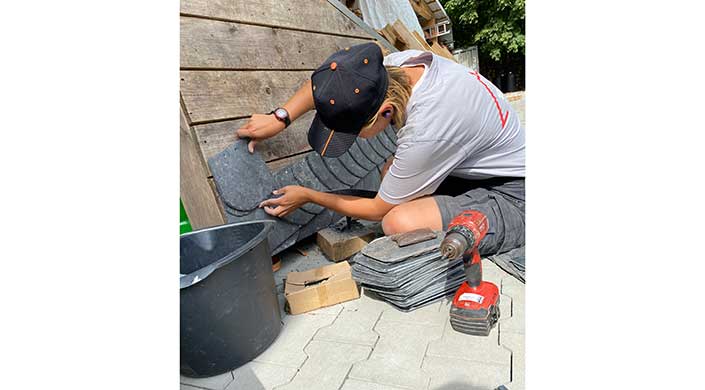 Bild von Dachdeckerin Janina Müller bei der Arbeit mit Schieferplatten