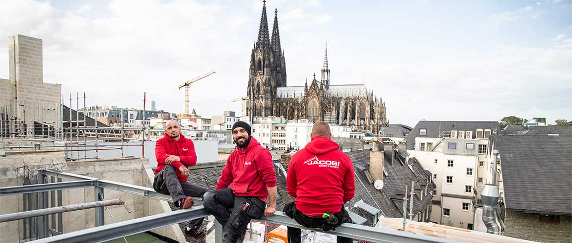 Bild von Mitarbeitern von Jacobi Dächer & Gerüste auf einem Dach mit Blick auf den Dom