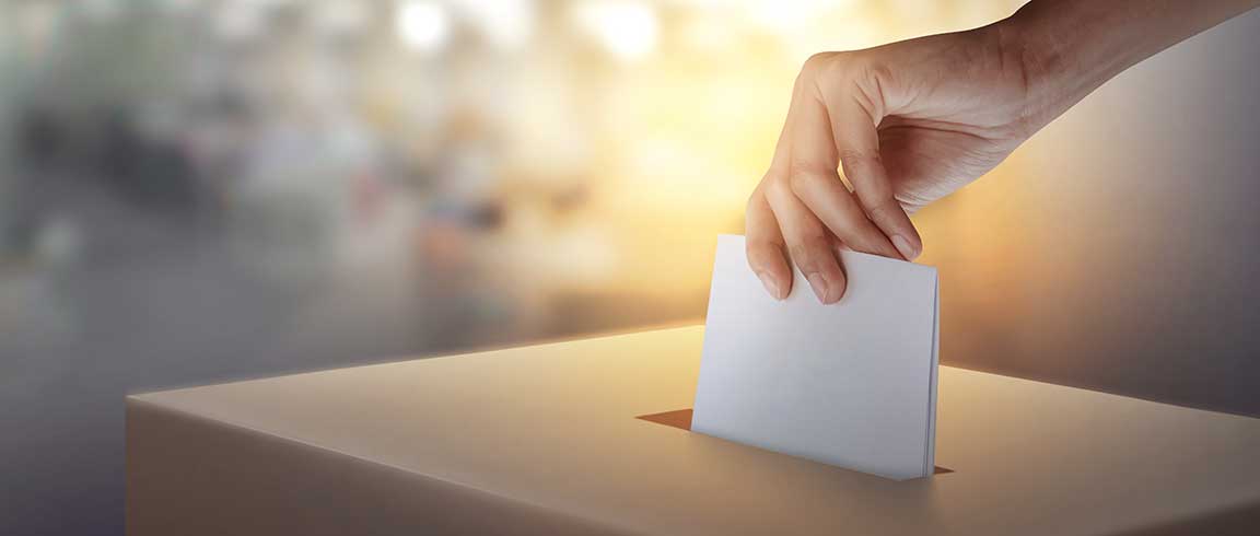 Bild von Hand, die Stimmzettel in Wahlurne wirft