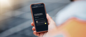 Eine Hand hält ein Smartphone mit einer geöffneten App auf Deutsch, die technische Informationen und Support anzeigt.