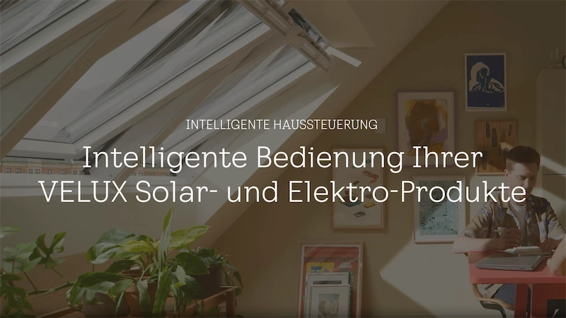 Intelligente Haussteuerung VELUX Oberlichtfenster in einem schrägen Dach, teilweise geöffnet, mit einfallendem Tageslicht. Ein Wandbild und Hauspflanzen sind darunter sichtbar.