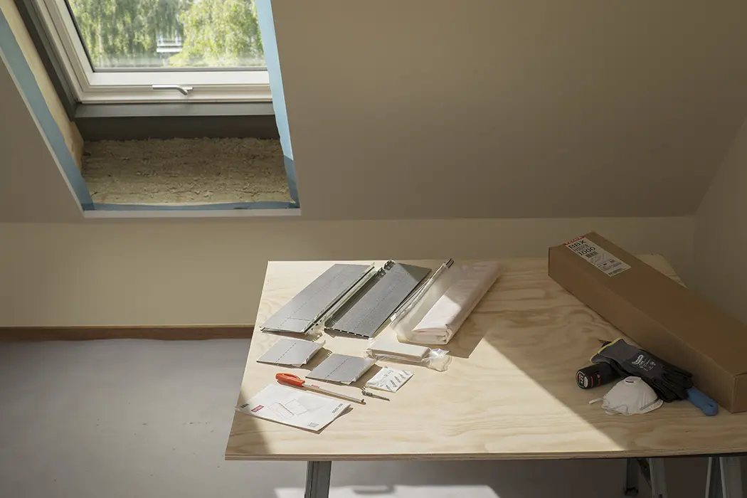 Mehrere graue Notizbücher mit Stift liegen auf einem hellen Holztisch vor neutralem Hintergrund.